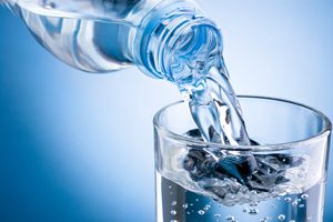 Bottle of Water Pouring into Glass